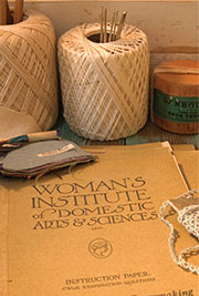 Thread, needles, and other needlework supplies, with an open book—Woman’s Institute of Domestic Arts and Sciences—Merit Badge Requirements